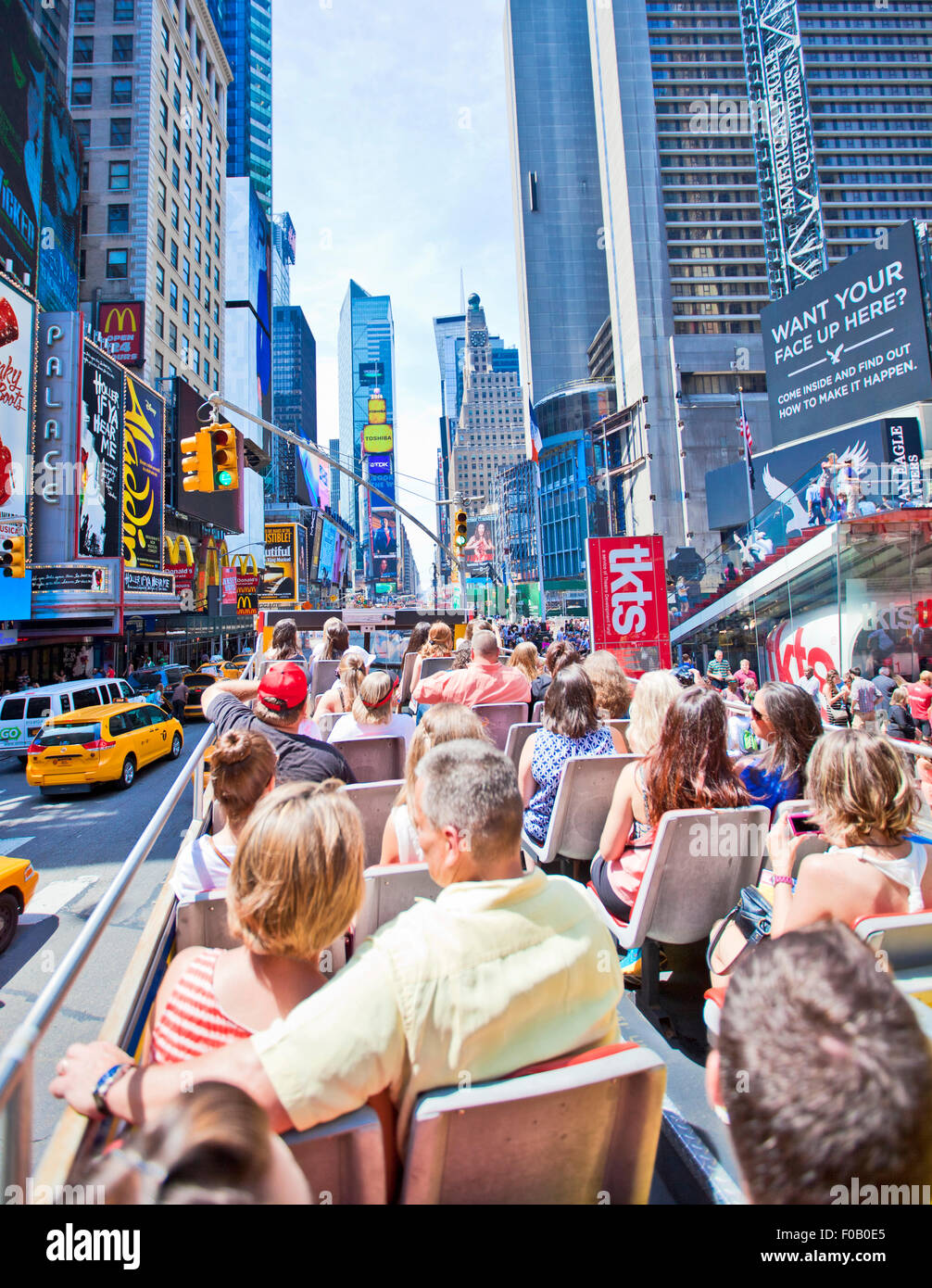 NEW YORK, USA - JUNE 28th 2014: Tourists taking a tour bus enjoying the sights of Times Square Stock Photo