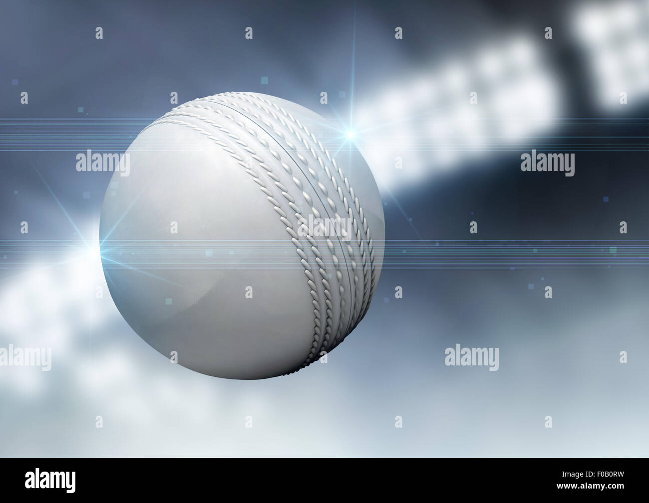 A regular white cricket ball flying through the air on an indoor stadium background during the night Stock Photo