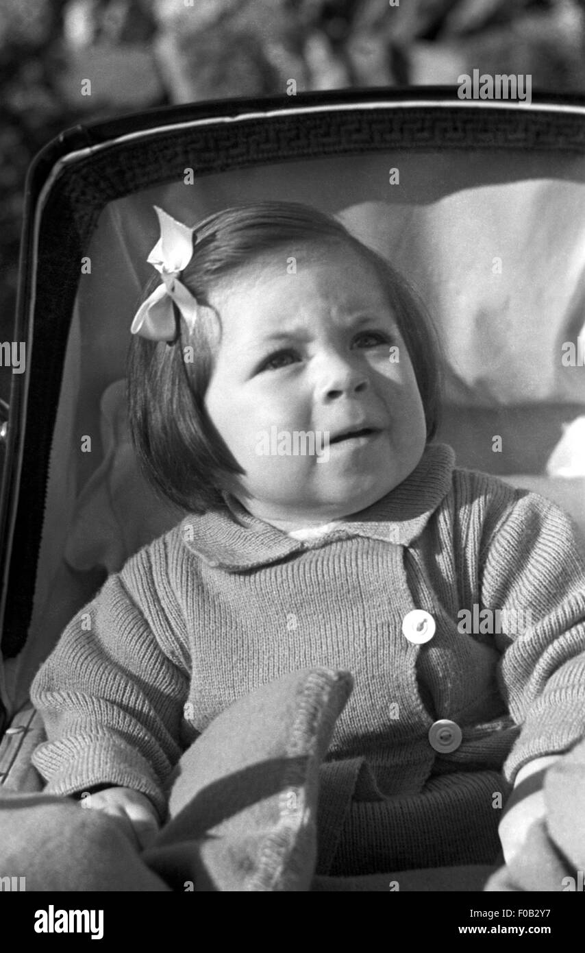A little girl sitting in a pram. Stock Photo