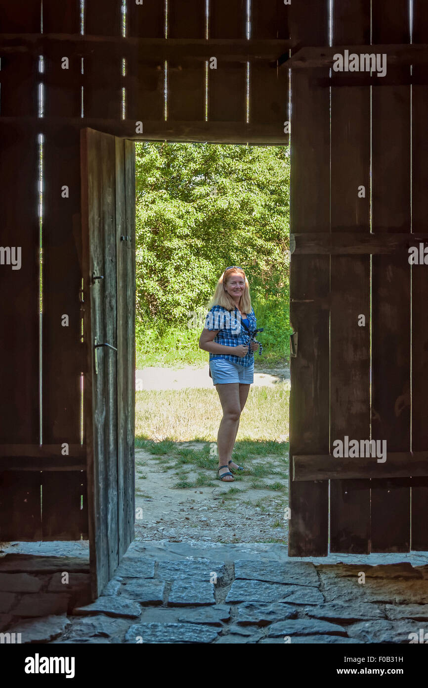 Woman seen through open wooden gate in Tokarnia open-air museum, Poland ...