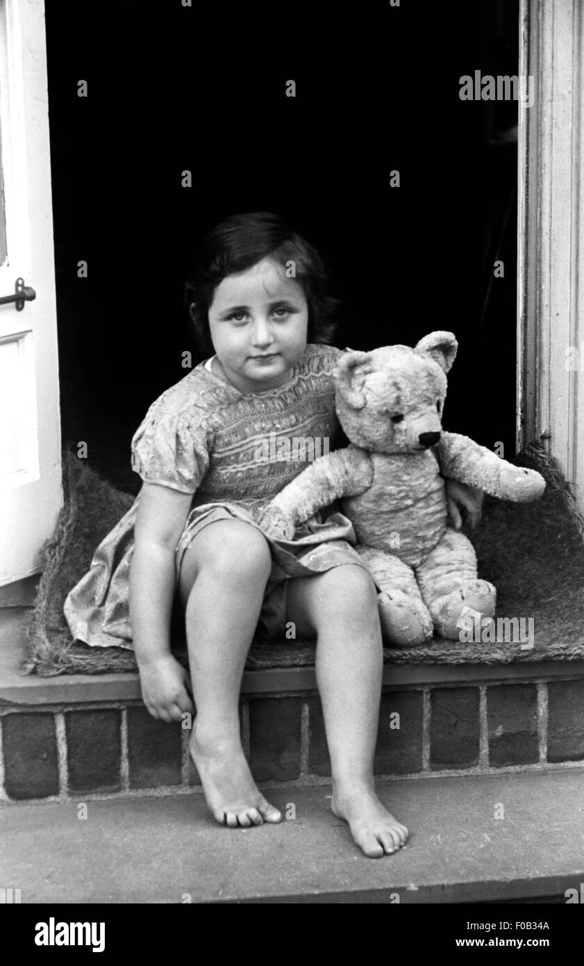A little girl sitting on a doorstep with her teddy bear Stock Photo - Alamy
