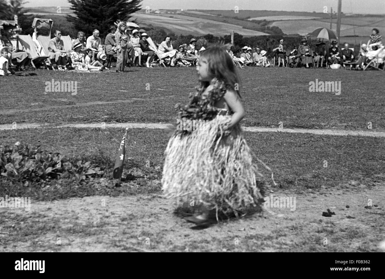 A little young girl in an Hawaiian dress and flowers around her neck at an event. Stock Photo