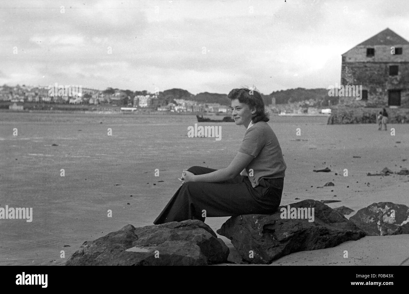 A woman sitting on the rocks at Rock, Cornwall. Stock Photo
