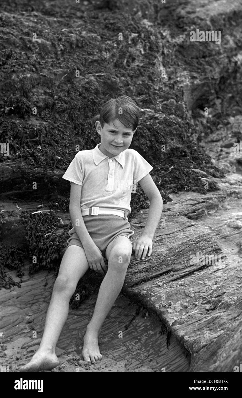 A young boy sitting on a rock at the seaside. Stock Photo