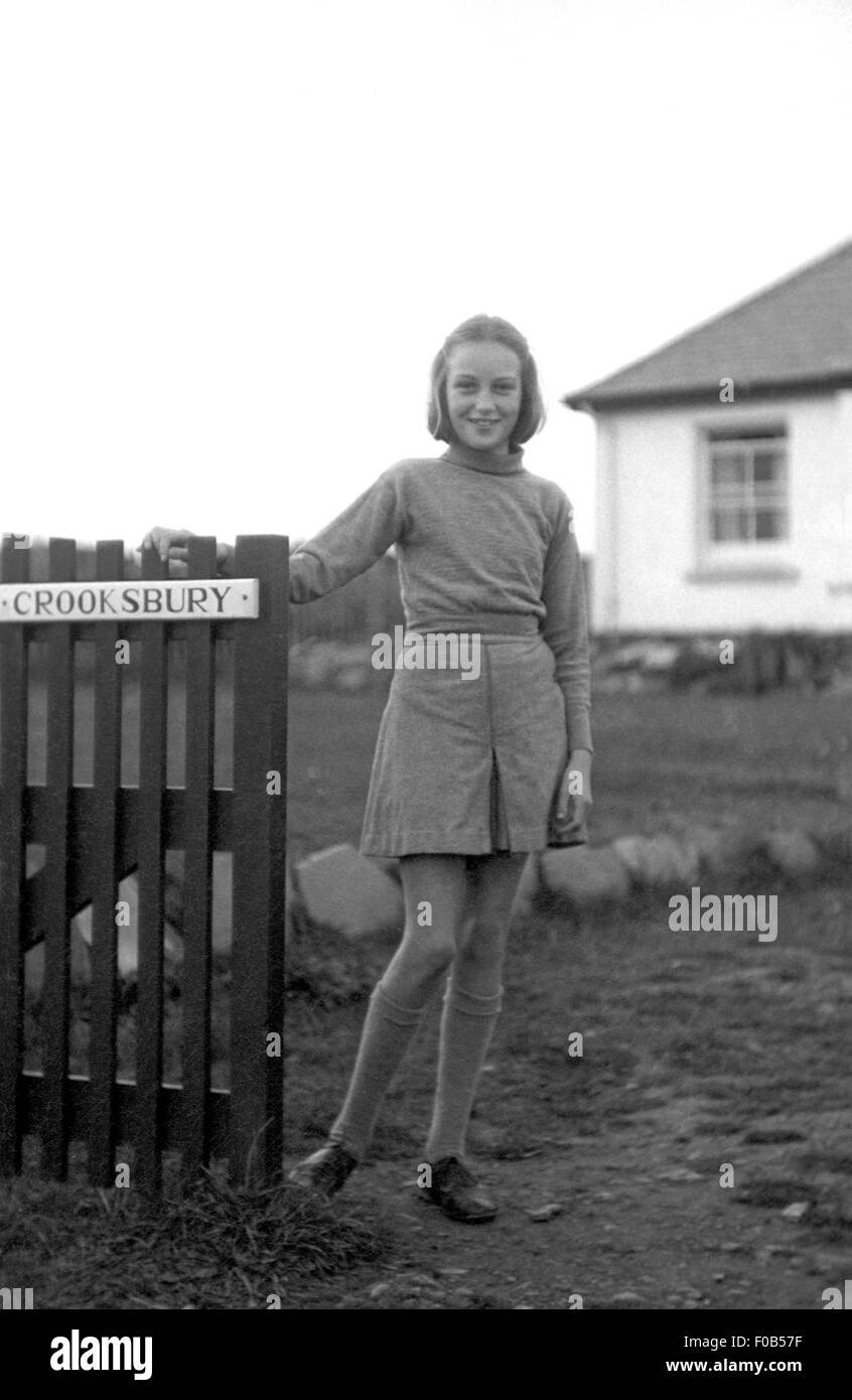 A tall young girl stands by the gate to a property Stock Photo