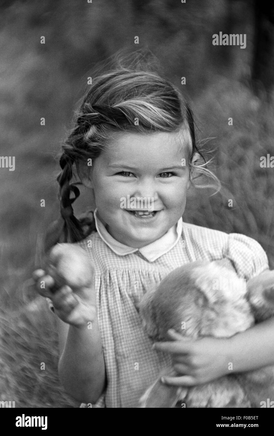 A little girl holding her teddy bear in the garden Stock Photo - Alamy