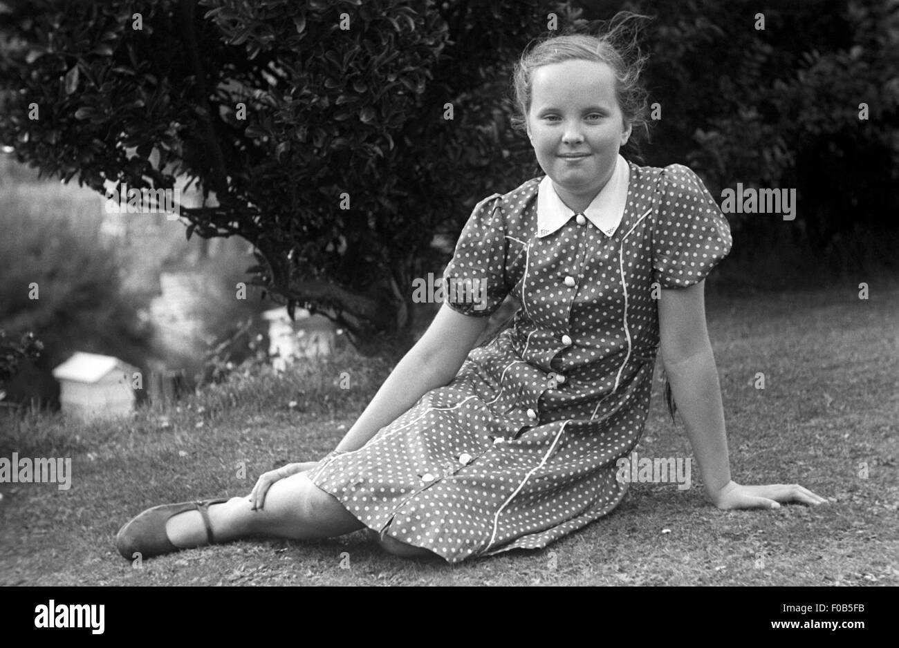 A young girl sitting on the grass in the garden Stock Photo - Alamy