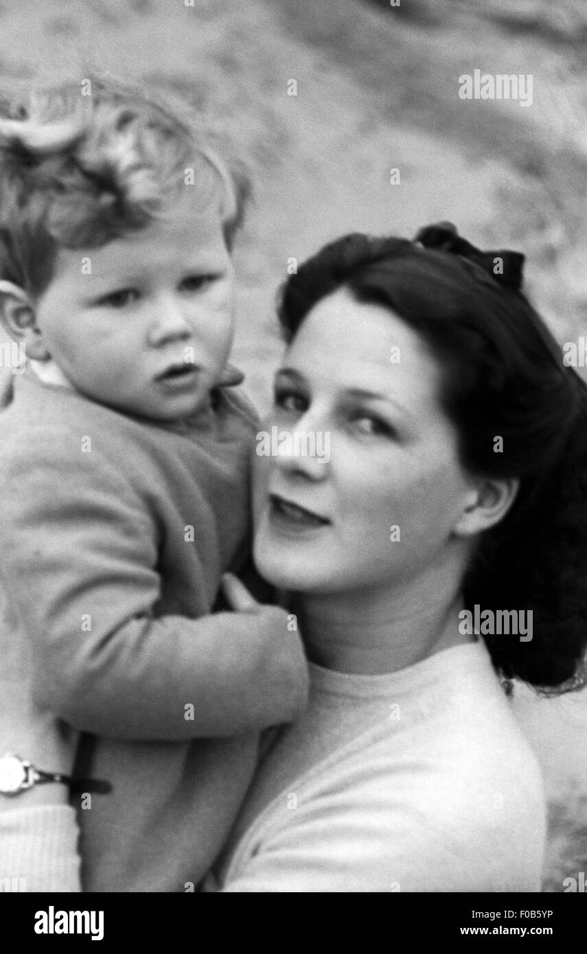 A dark haired woman holding her son looking at the camera. Stock Photo