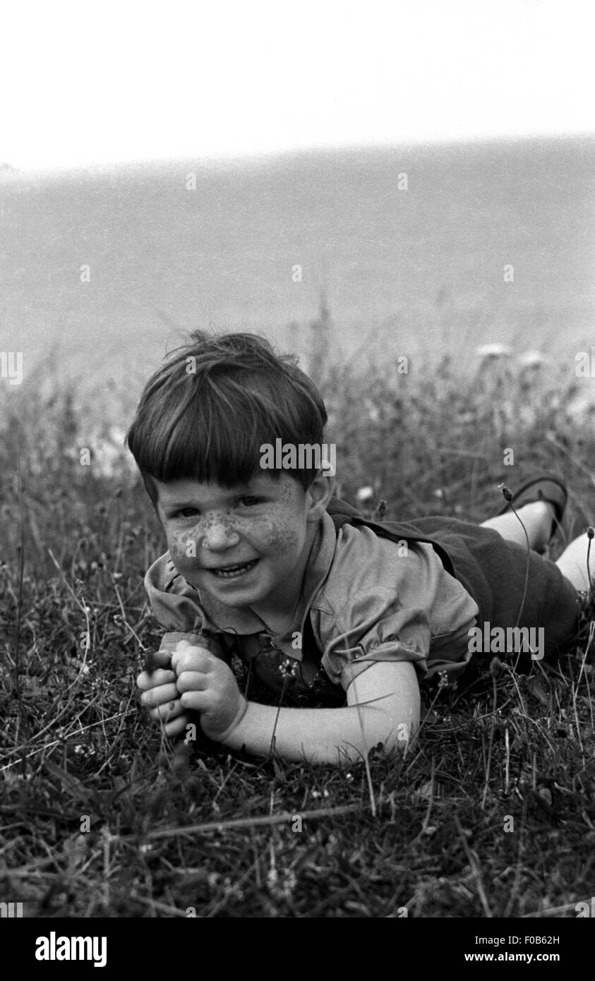 Dark haired little boy lying on grass Stock Photo