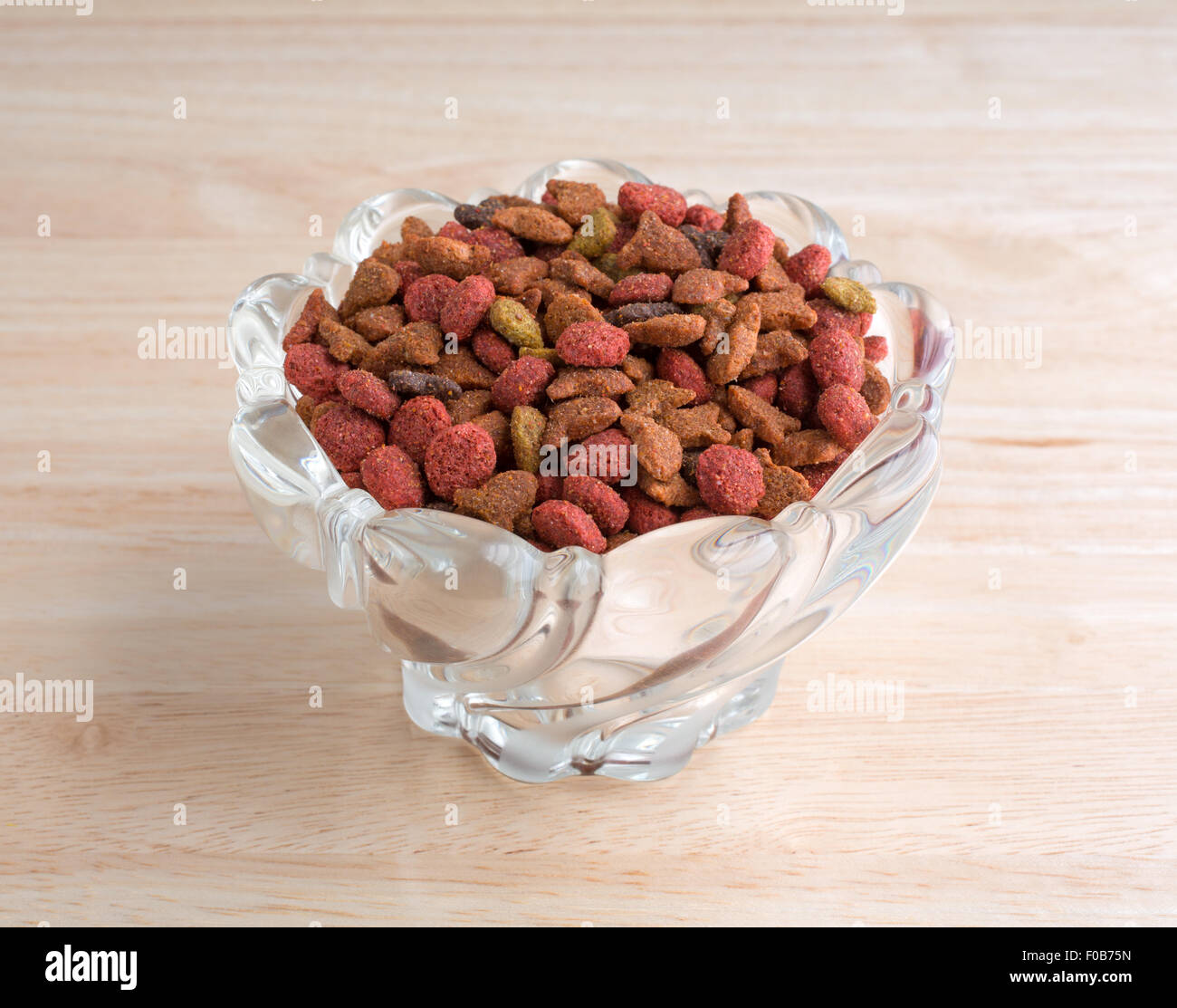 A decorative glass bowl filled with generic dry cat food on a wood counter  top Stock Photo - Alamy