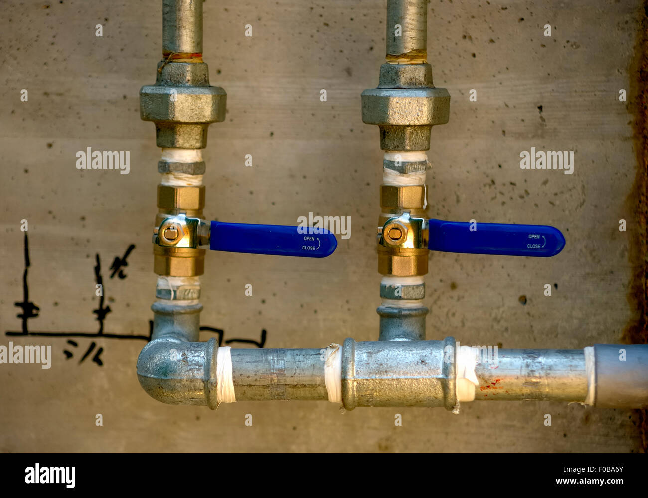 Galvanized steel tubes mounted on a concrete wall with its stopcocks Stock Photo