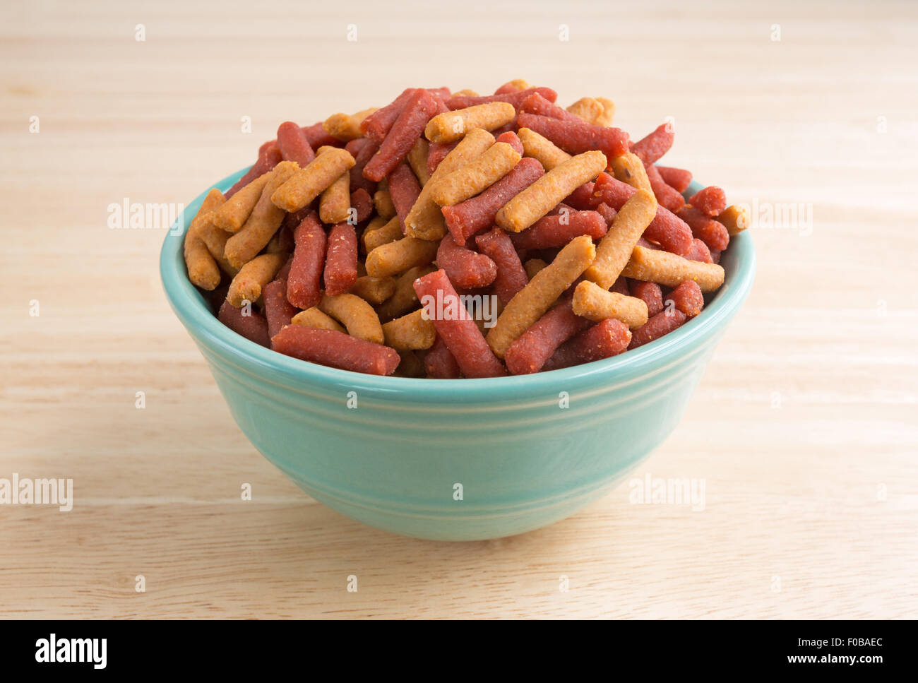 Side view of a small bowl of dog food sitting on a wood floor. Stock Photo