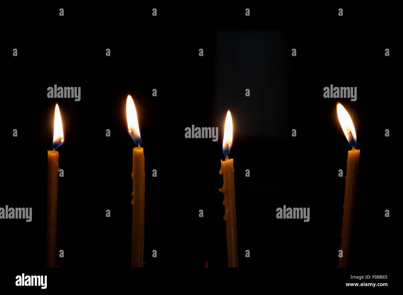 four alight candles over the black background Stock Photo - Alamy