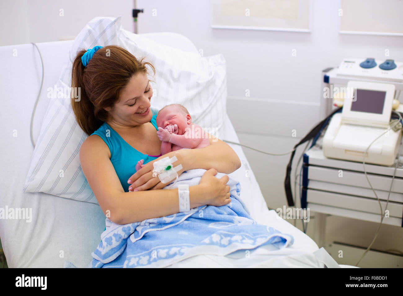 Mother giving birth to a baby. Newborn baby in delivery room. Mom holding her new born child after labor. Stock Photo