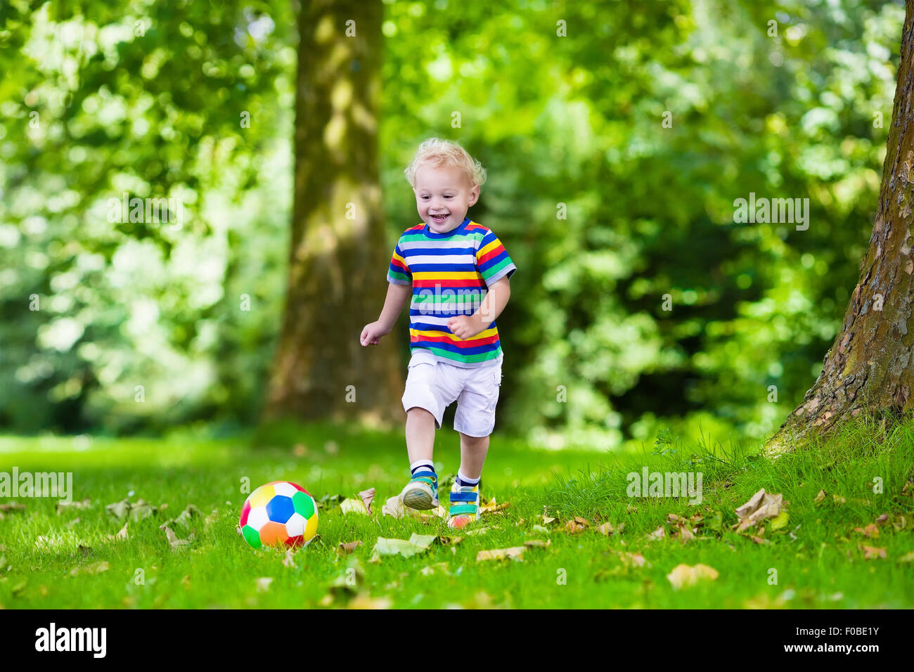 Happy child playing European football outdoors in school yard. Kids play soccer. Active sport for preschool child. Stock Photo