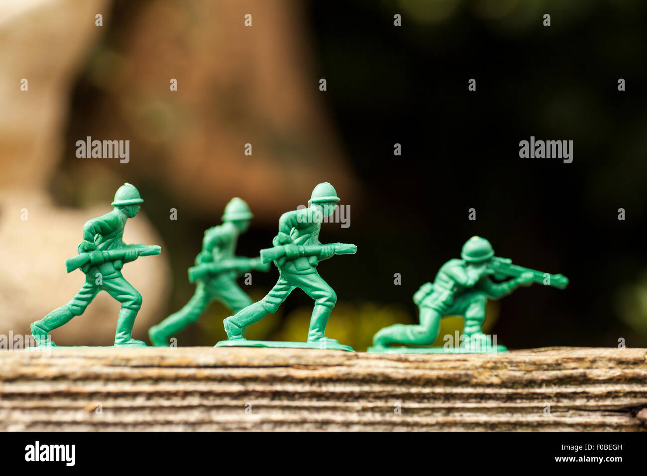 Green plastic toy soldiers/army men on a mission in the back garden surrounded by grass and flowers Stock Photo