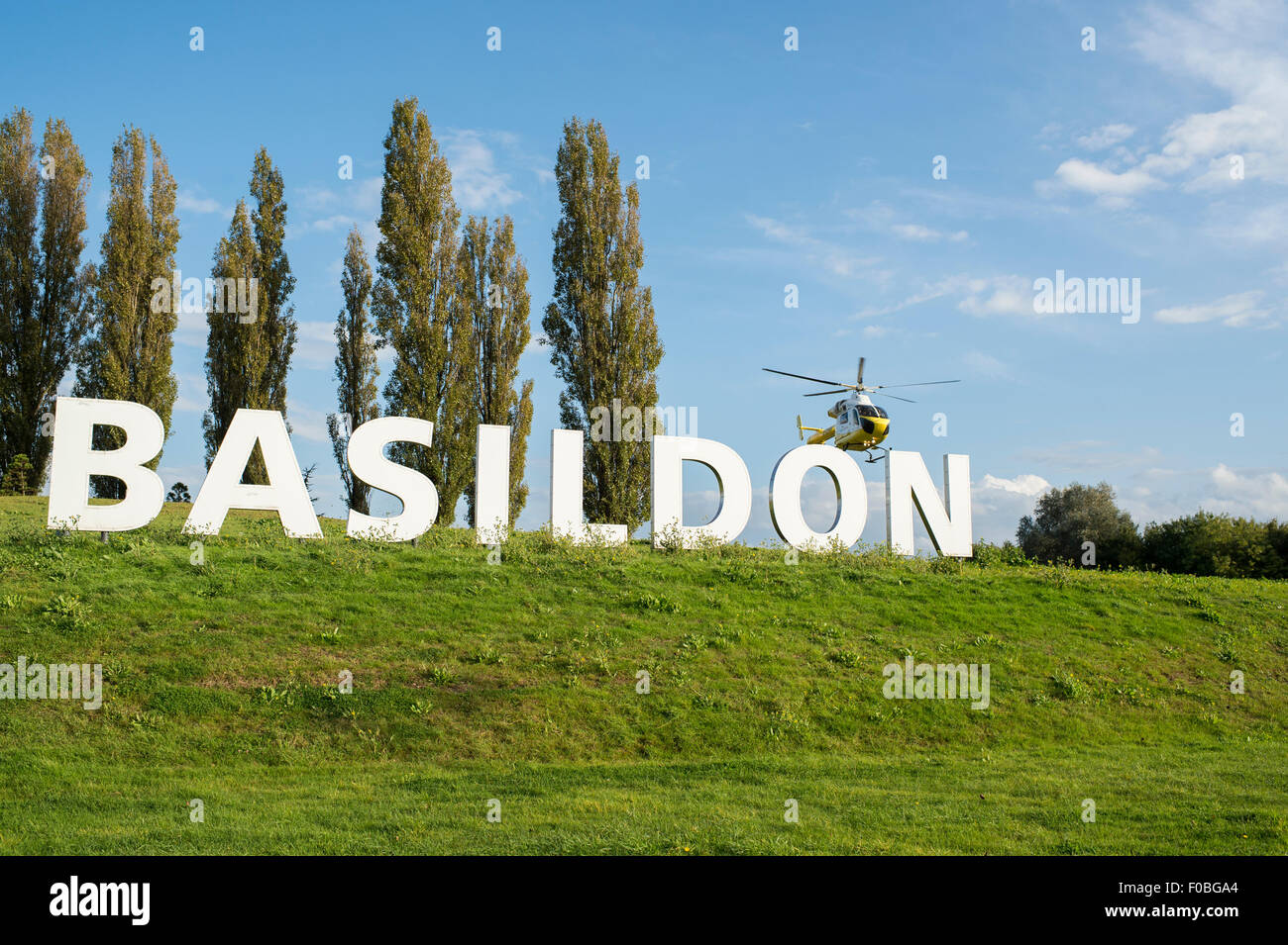 The now iconic Basildon sign at the entrance to the Essex town with the Herts and Essex Air Ambulance landing next to it. Stock Photo