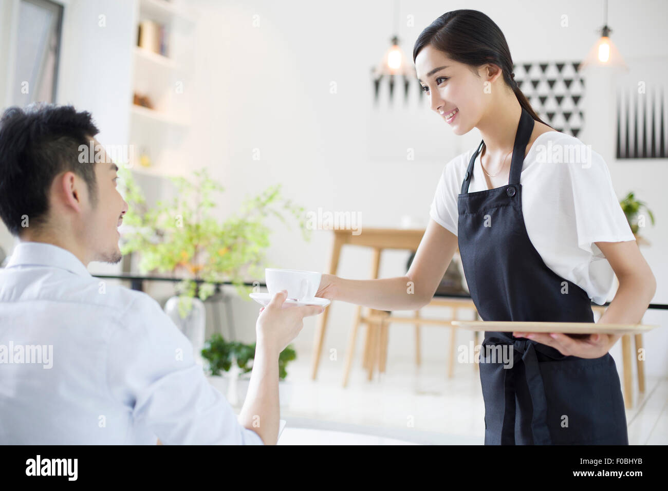 Waitressing Man Waitress serving young man a cup of coffee Stock Photo - Alamy