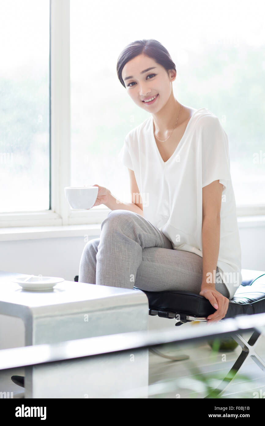 Happy young woman drinking coffee in coffee shop Stock Photo - Alamy