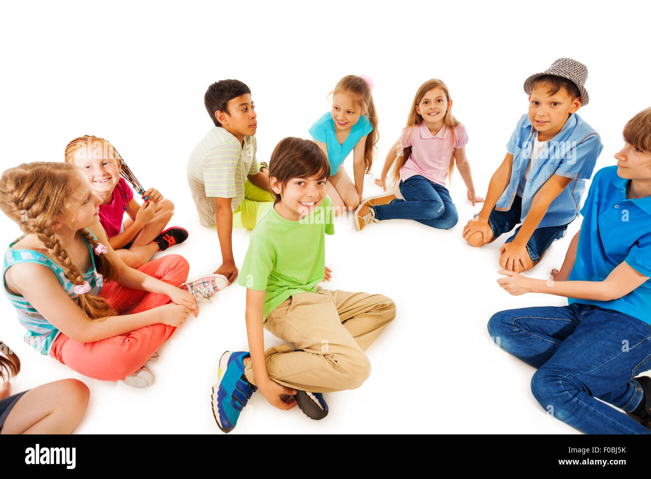 Kids sit in circle with one boy at center Stock Photo
