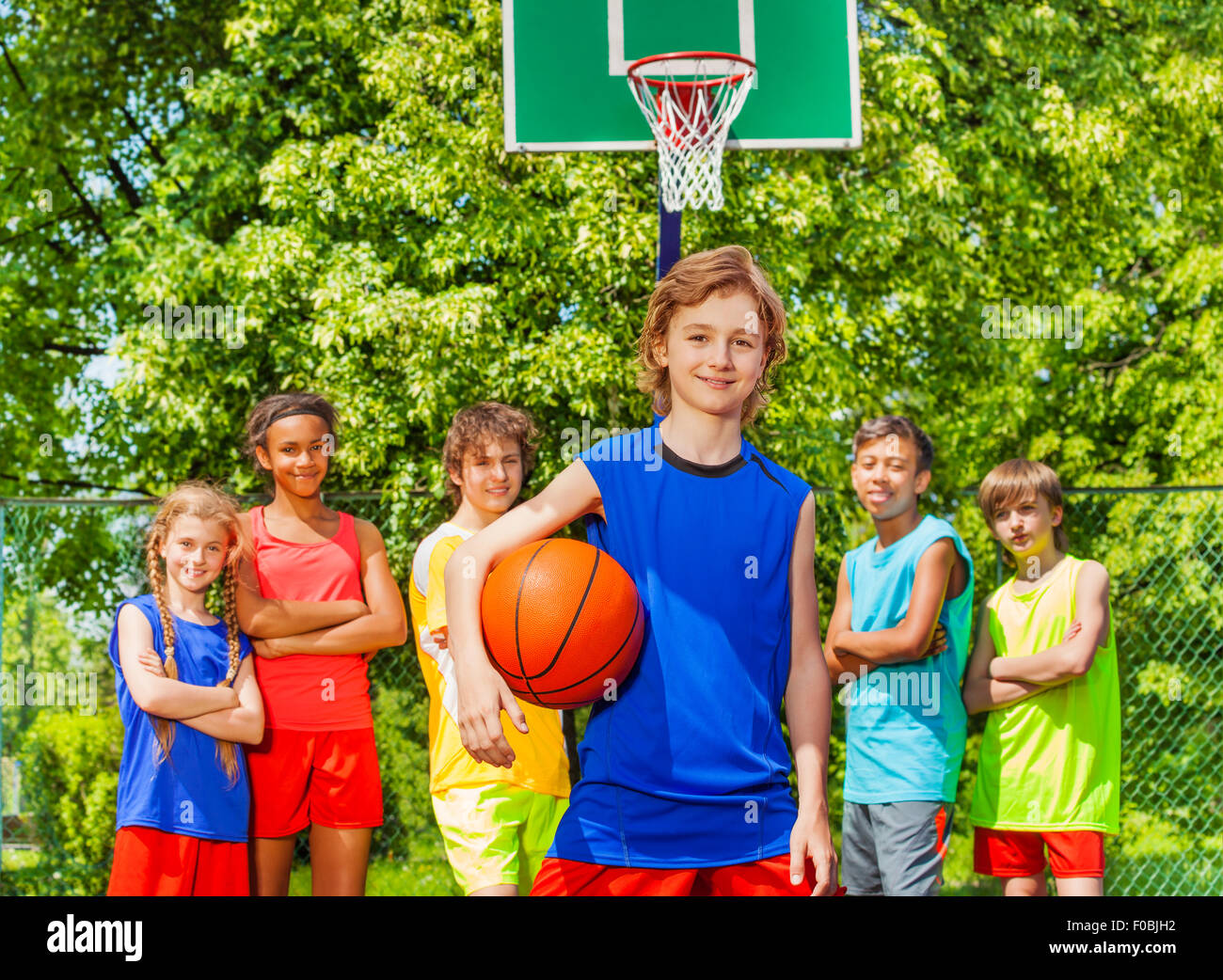 Cute boy with ball and happy friends behind Stock Photo
