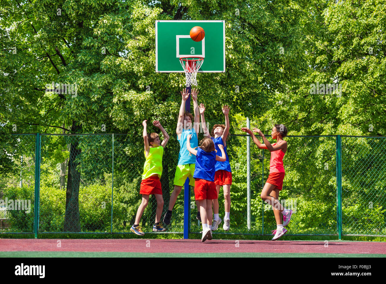 Happy teenagers playing basketball on playground Stock Photo Alamy
