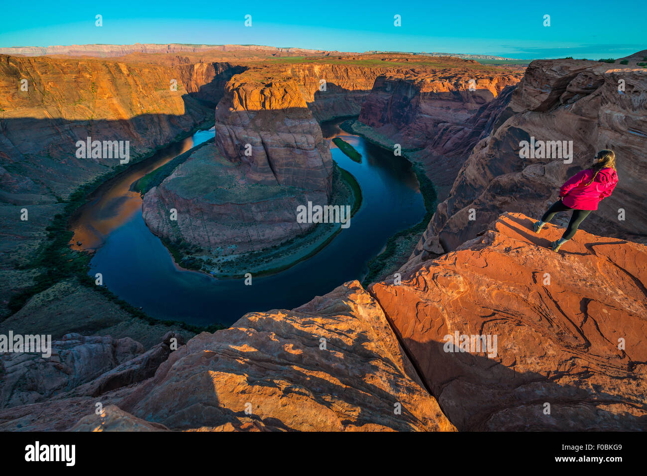 Girl Hiker Standing at the edge of Horseshoe Bend Page Arizona Sunrise Stock Photo