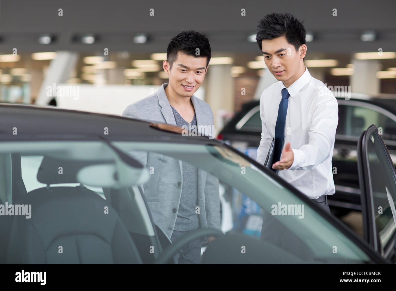 Young man choosing car in showroom Stock Photo