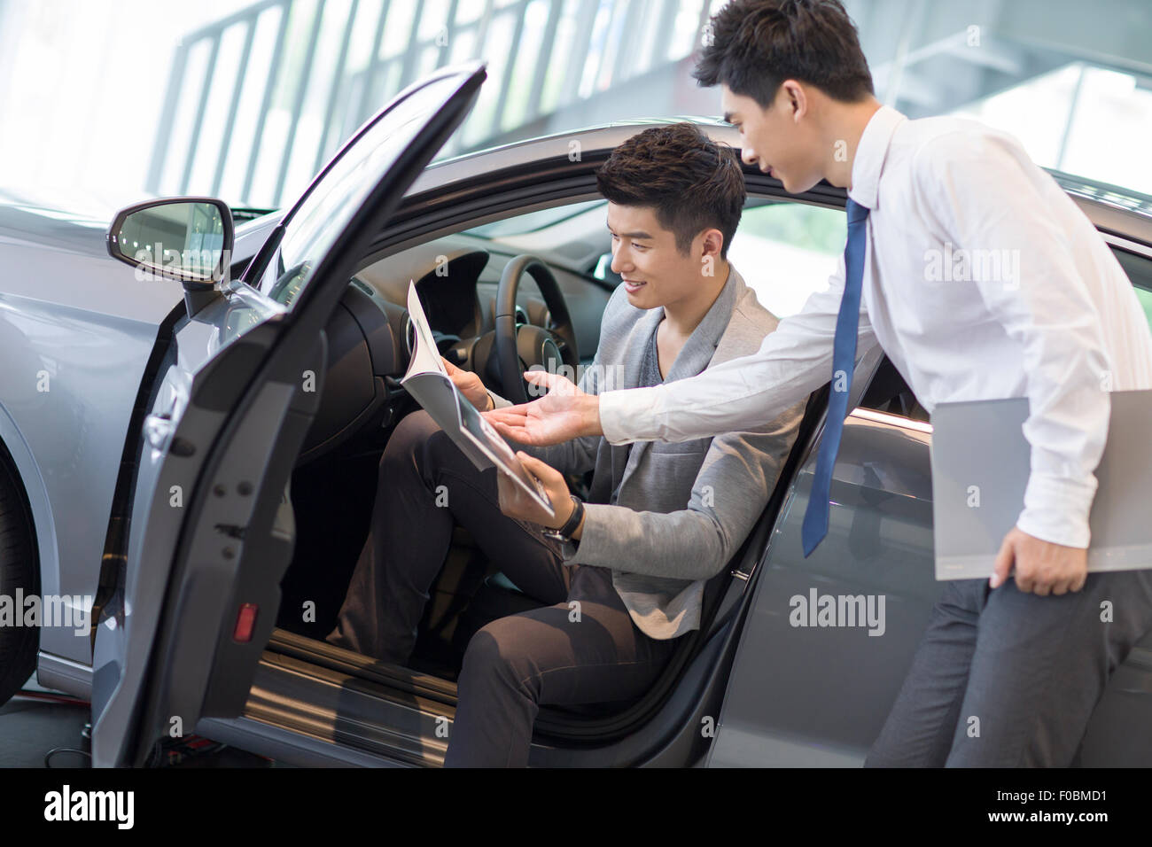 Young man choosing car in showroom Stock Photo