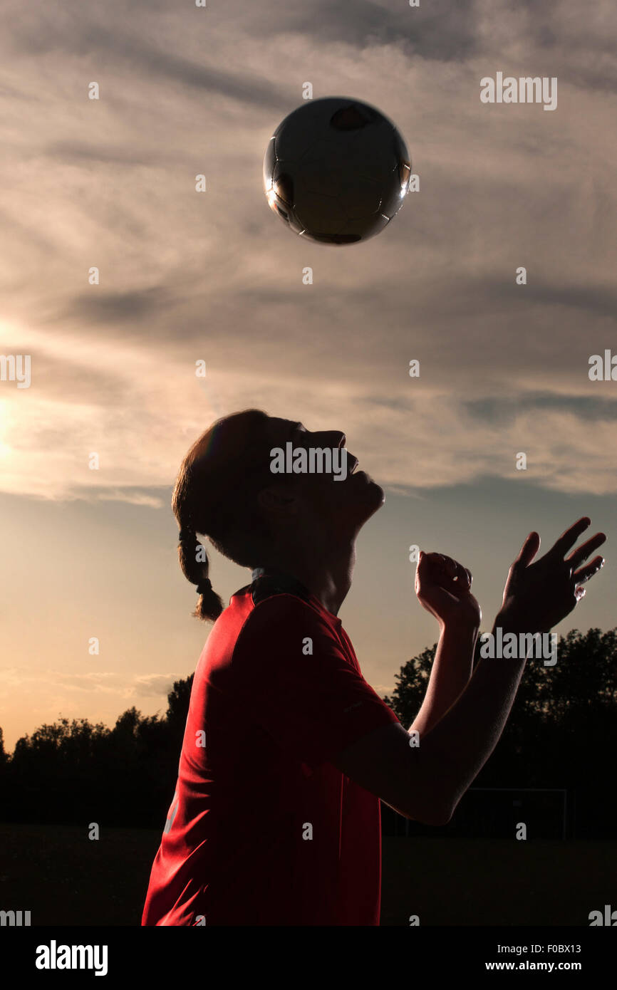 Side view of soccer player heading ball in field Stock Photo