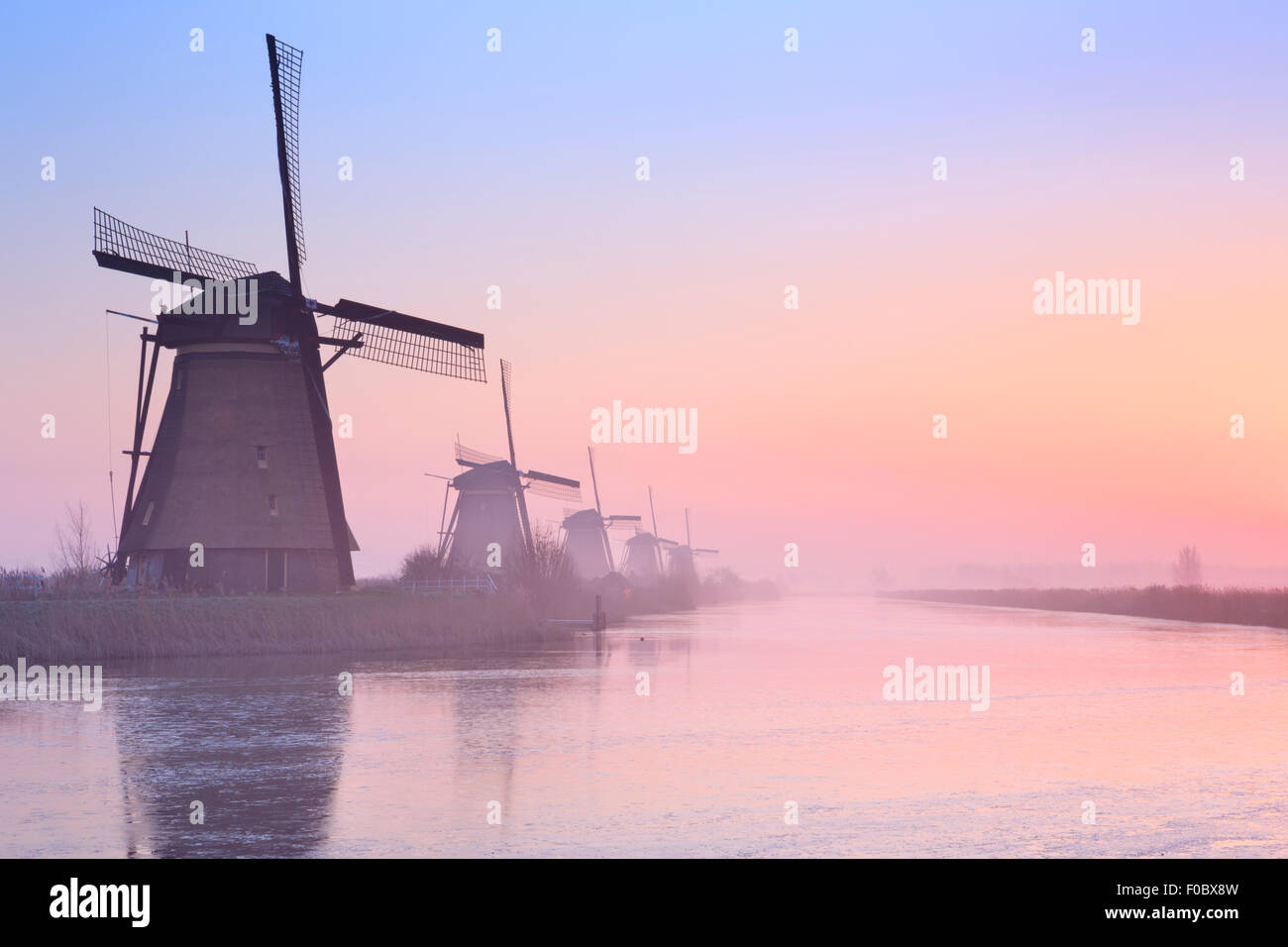 Traditional Dutch windmills on a cold morning at sunrise in winter, at the Kinderdijk in The Netherlands. Stock Photo