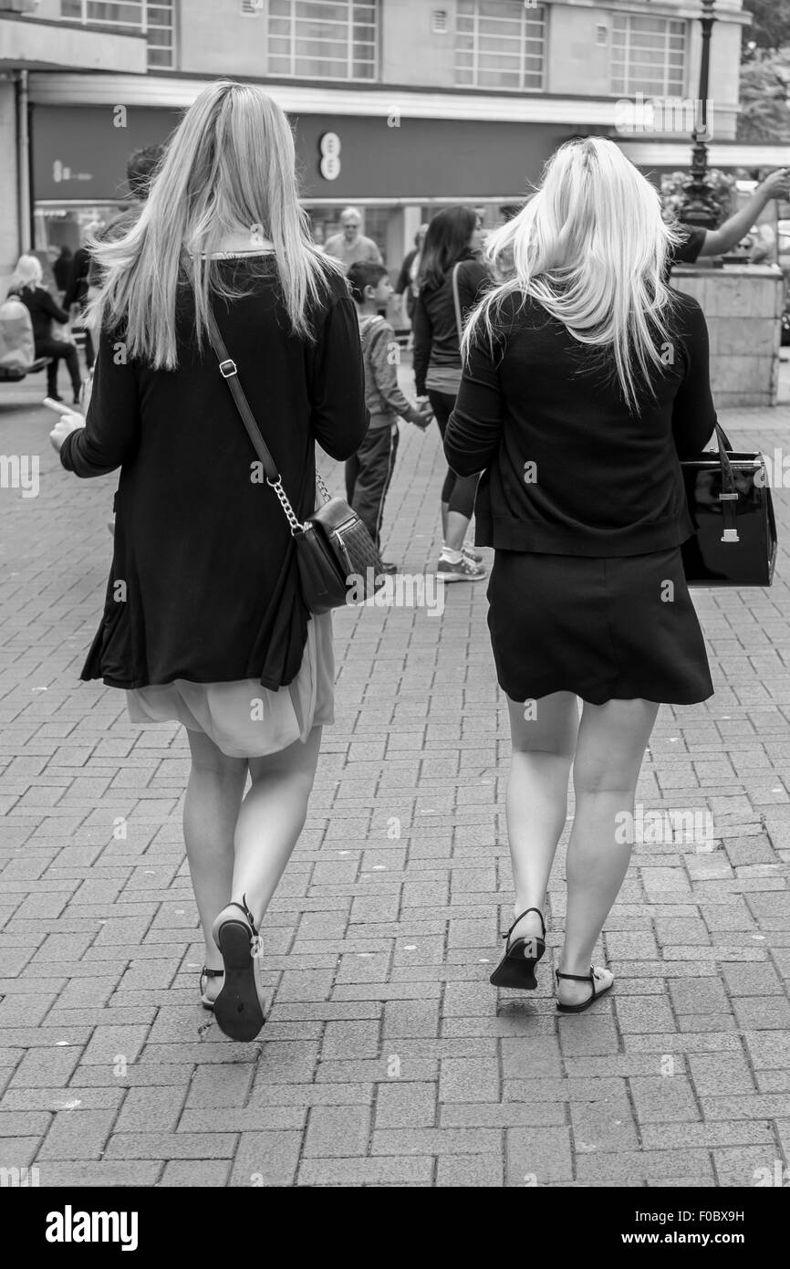 Two Blonde Tourists walking through Bournemouth shopping centre chatting and walking together. Stock Photo
