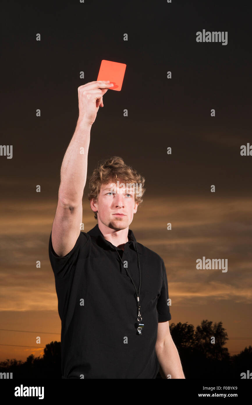 Young soccer referee holding up red card during sunset Stock Photo