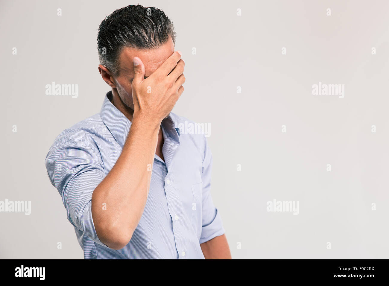 Portrait of a handsome man covering his eyes with hands isolated on a ...