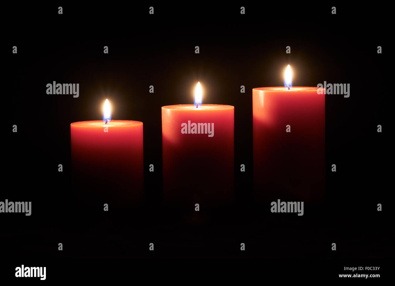 Lit red candles on a dark wooden floor with black background Stock
