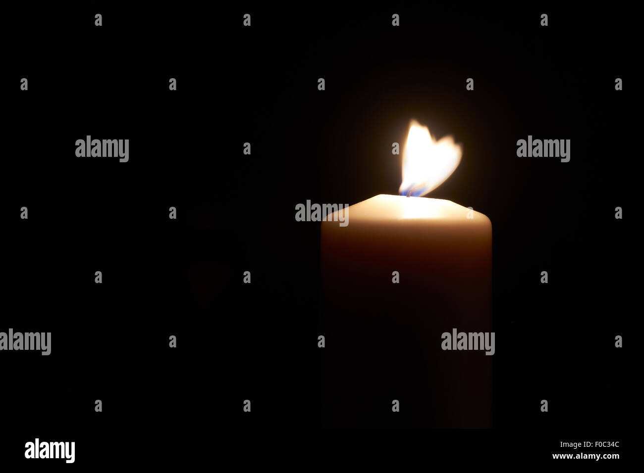 Wind blowing lit white candle on a dark  black background. Stock Photo