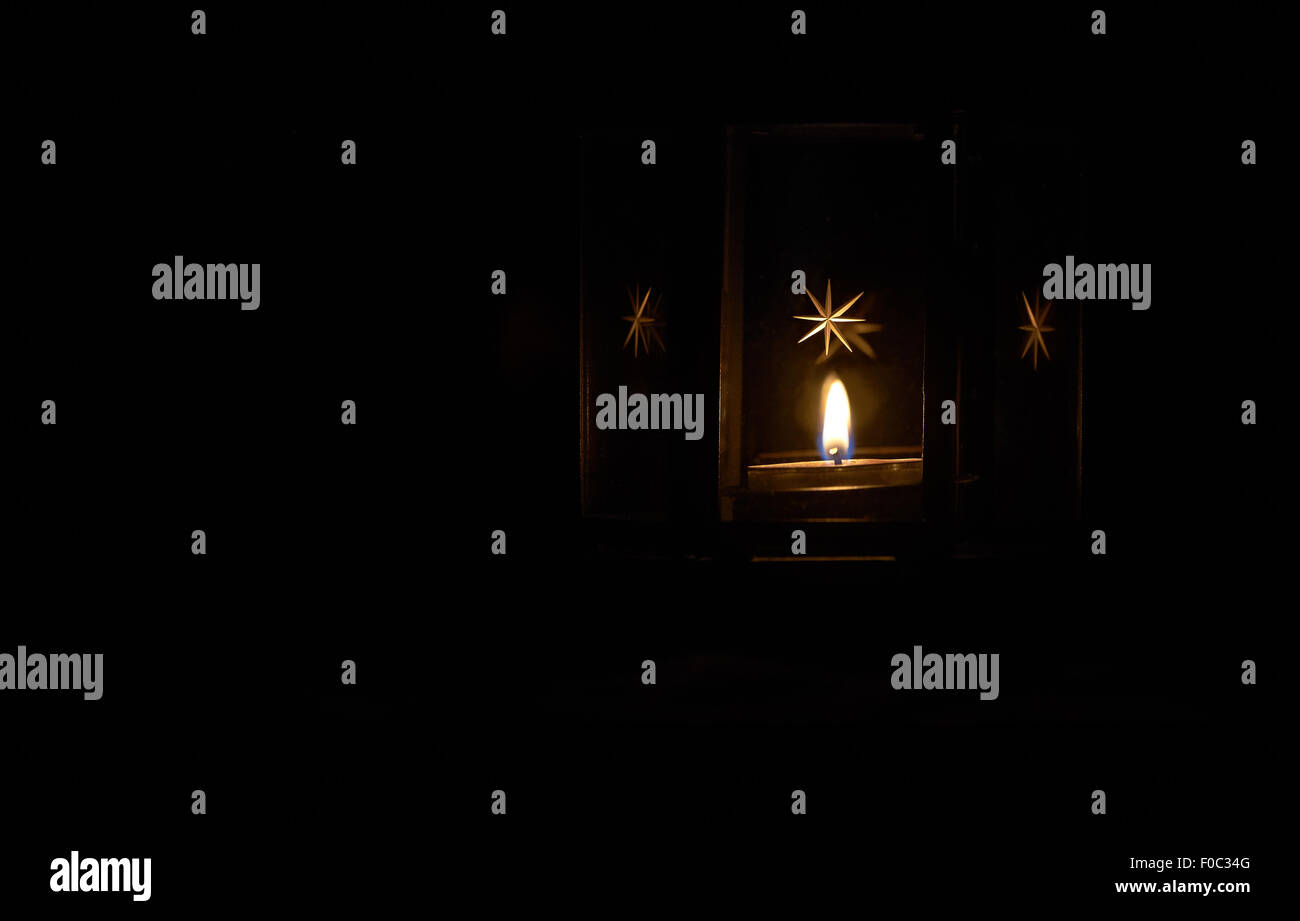 A tealight candle in a festive lantern in a dark room Stock Photo