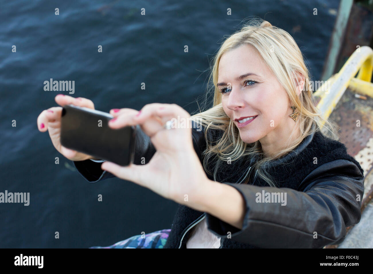 blond woman by the waterfront taking a selfie Stock Photo - Alamy
