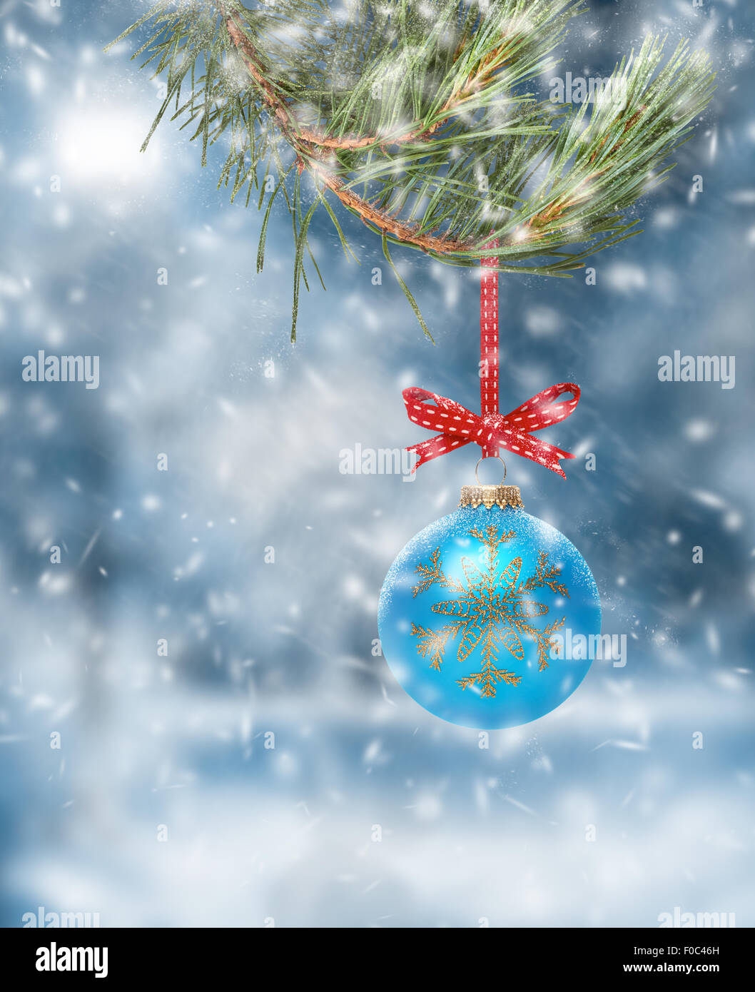 Traditional Christmas Tree Decoration hanging from a tree branch with a snow scene background. Stock Photo