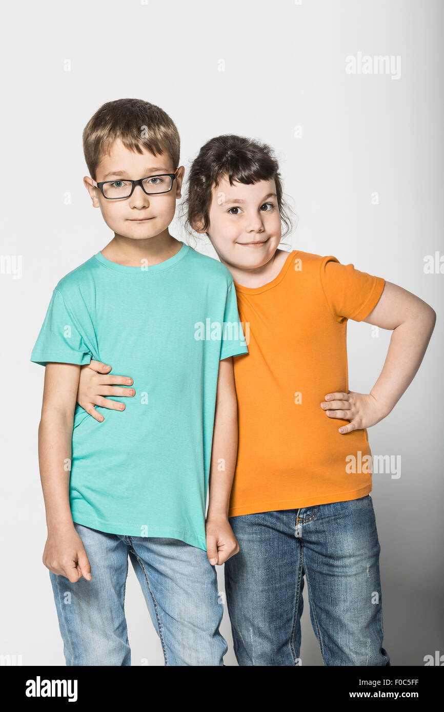 Portrait of brother and sister standing arm around against white background Stock Photo