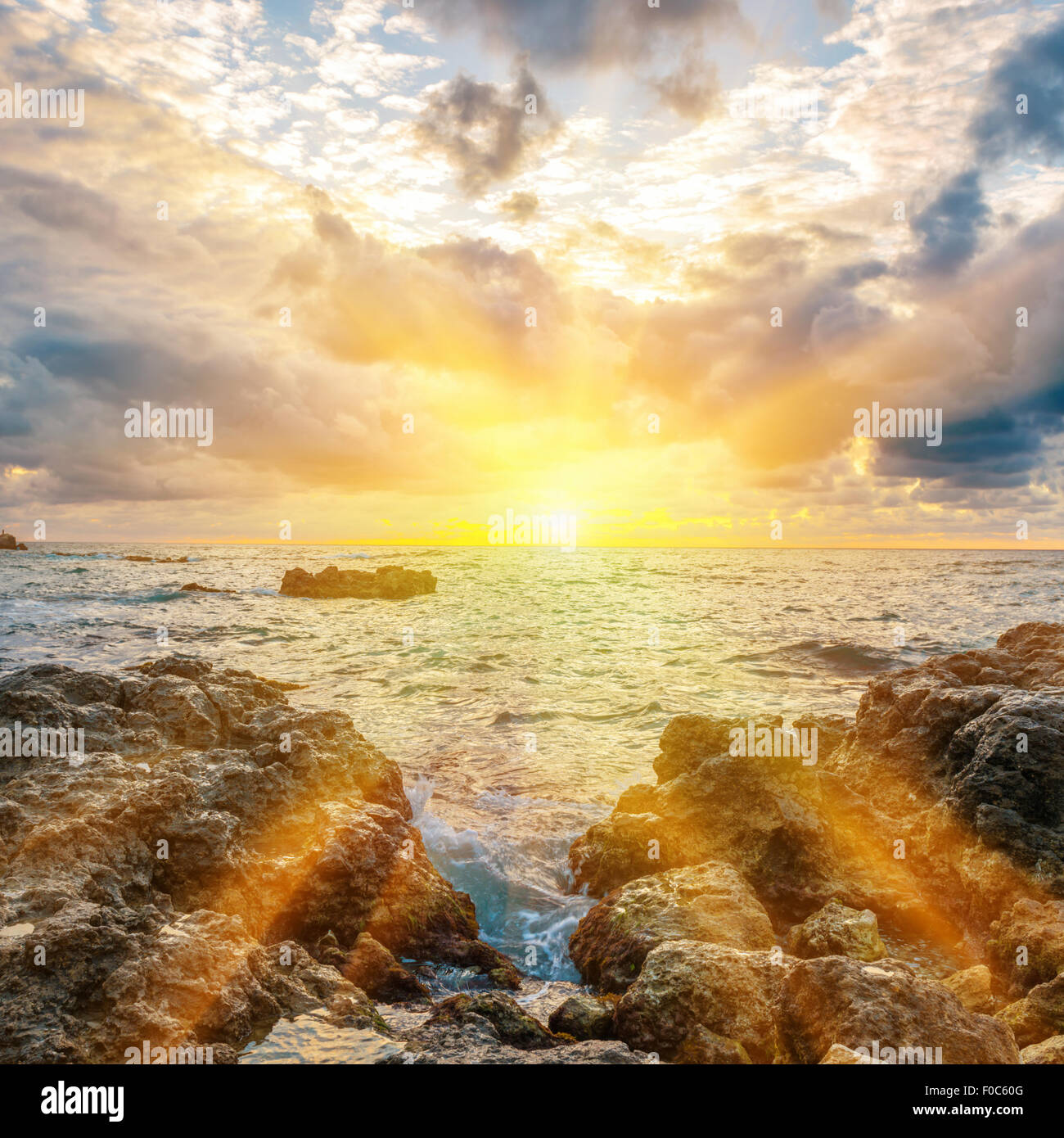 Sunset on the beach with waves, sea, rocks and dramatic sky Stock Photo ...