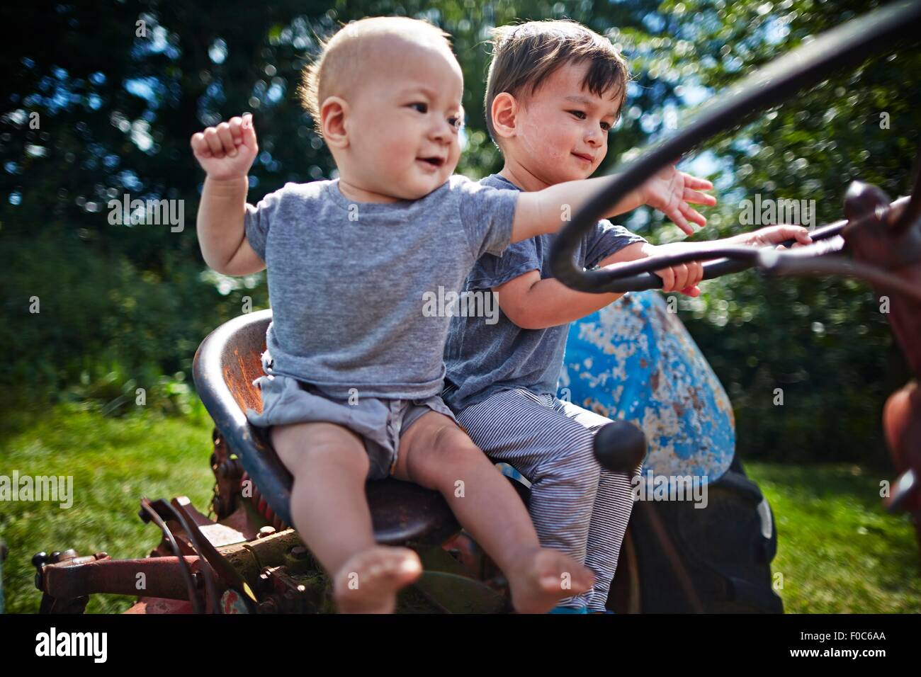 Baby boy and boy playing on old tractor Stock Photo Alamy