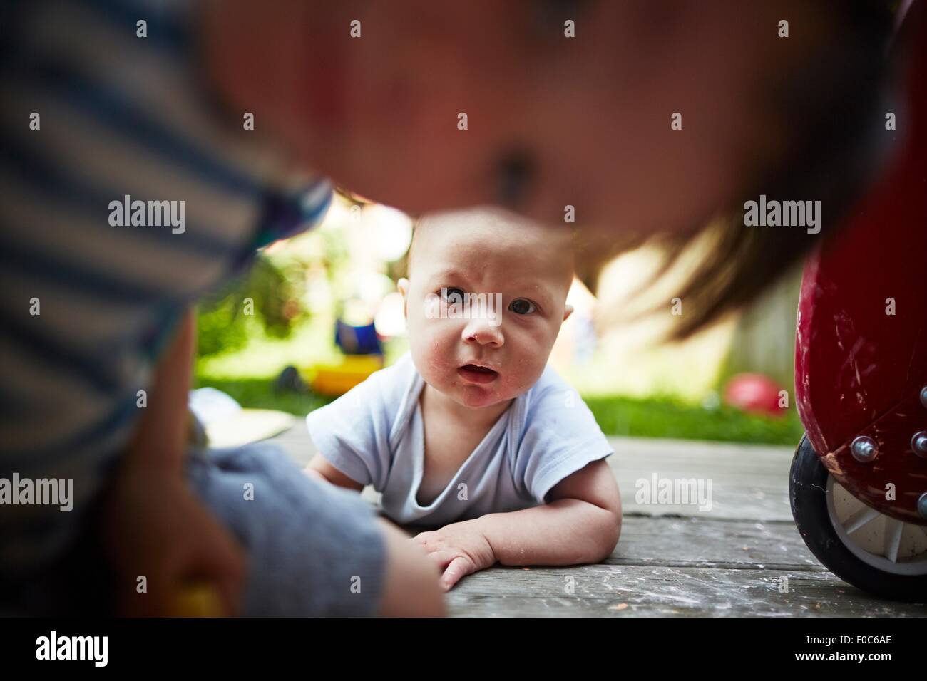 Portrait of baby boy lying down looking at camera with older brother in foreground Stock Photo