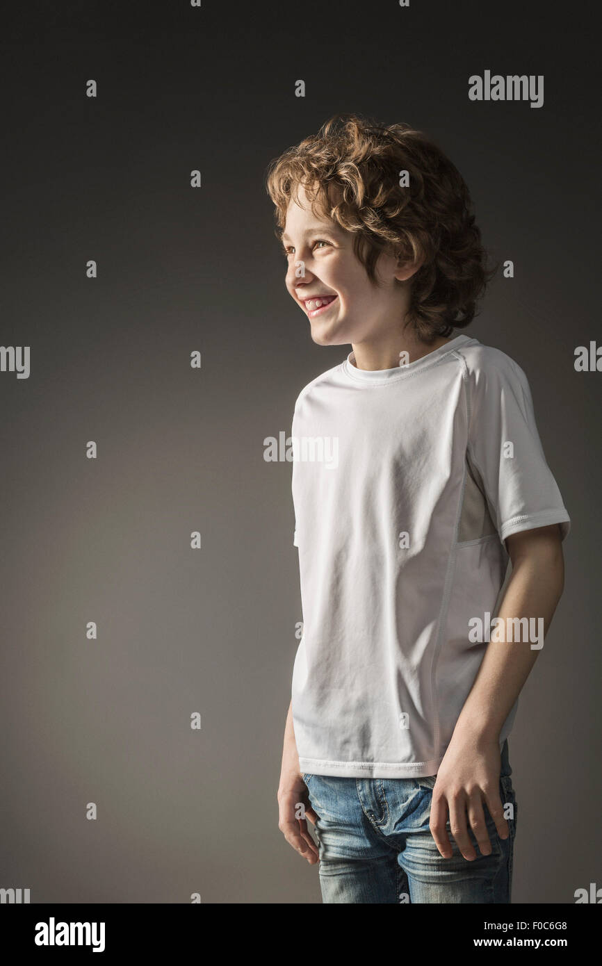 Young boy smiling while looking away over gray background Stock Photo ...