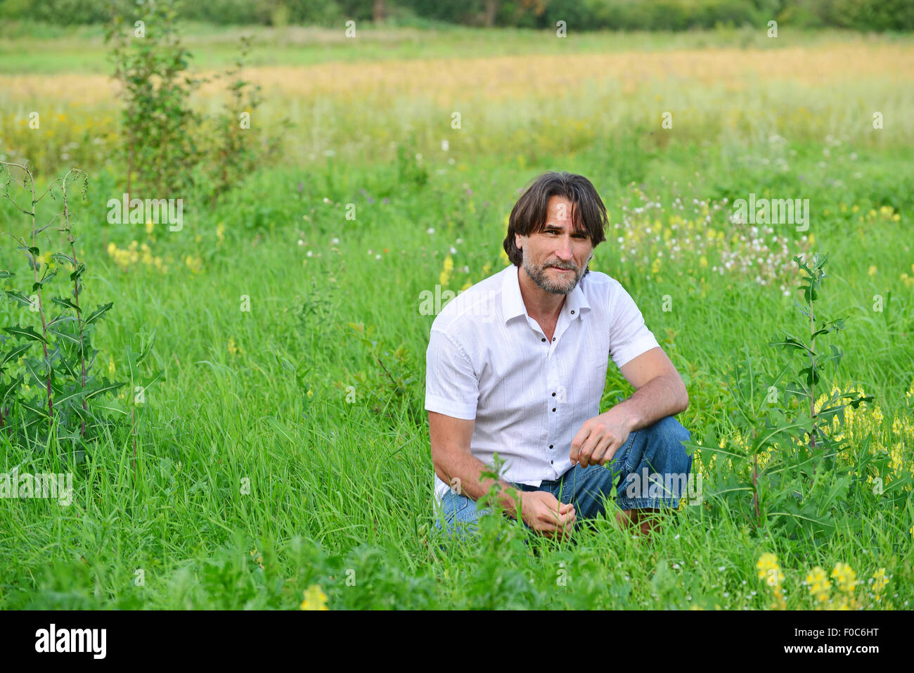 A man sits in the  grass in the summer Stock Photo