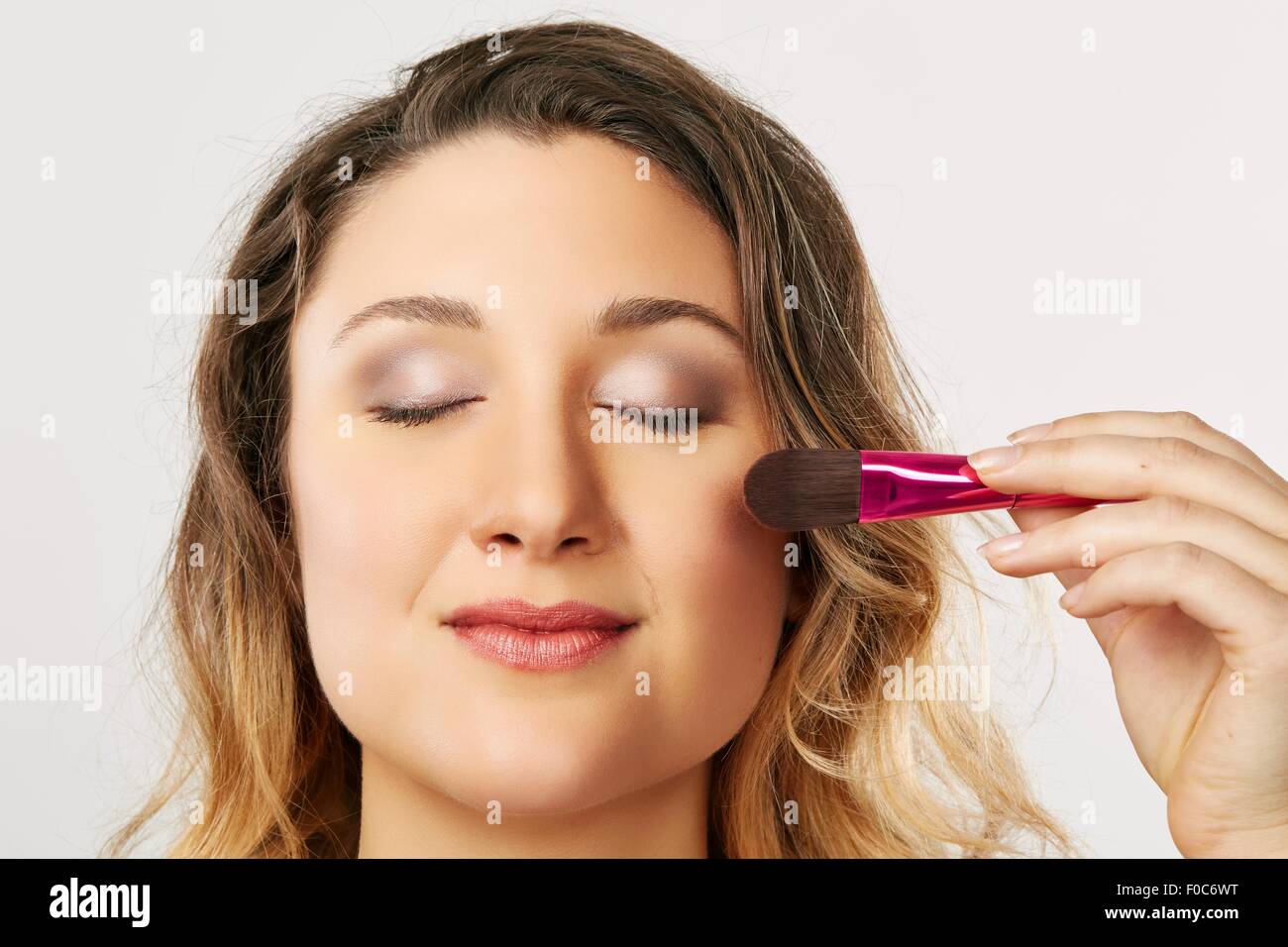 Young woman using blusher brush Stock Photo