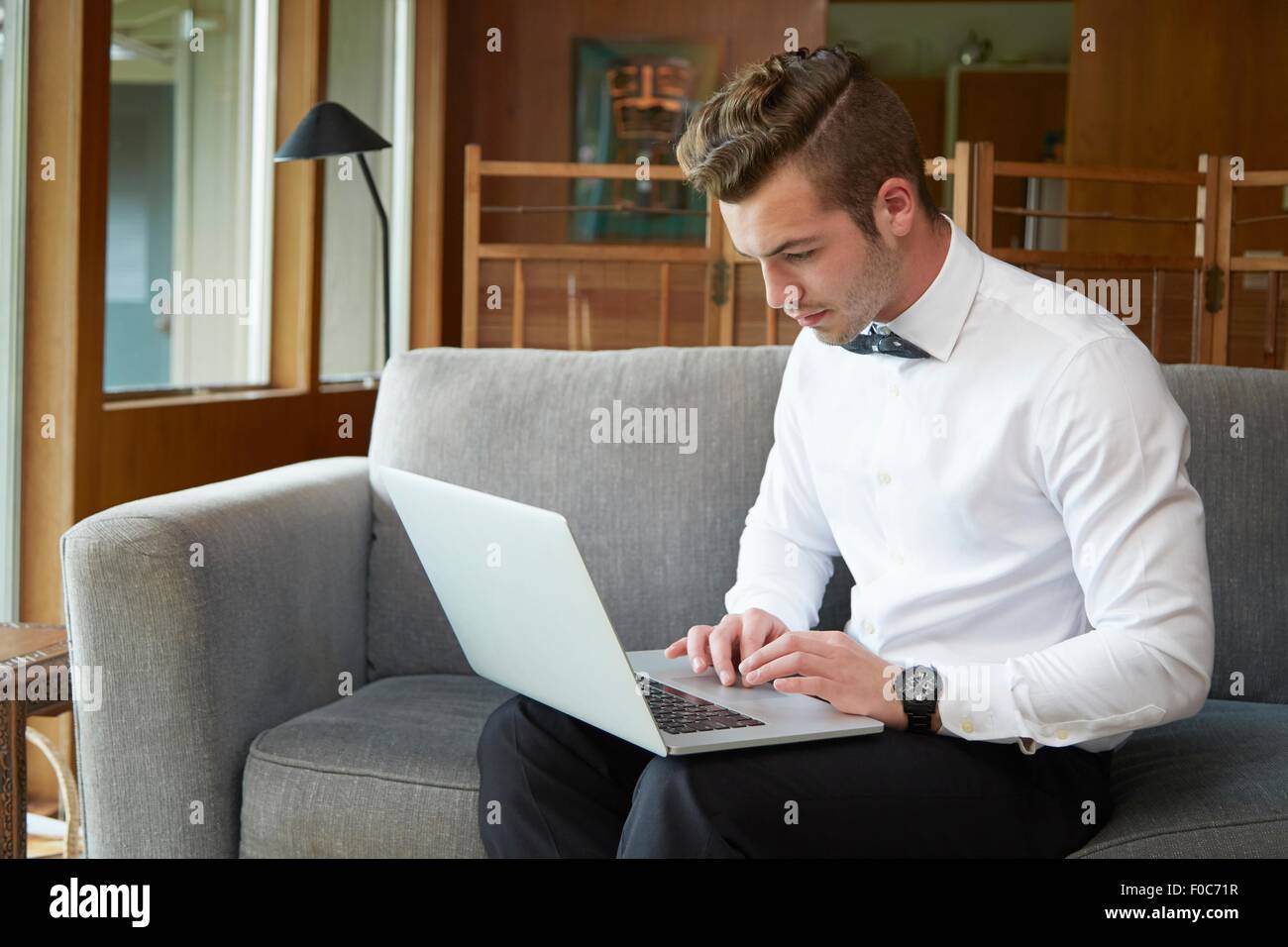 Portrait of man sitting on sofa working from laptop Stock Photo