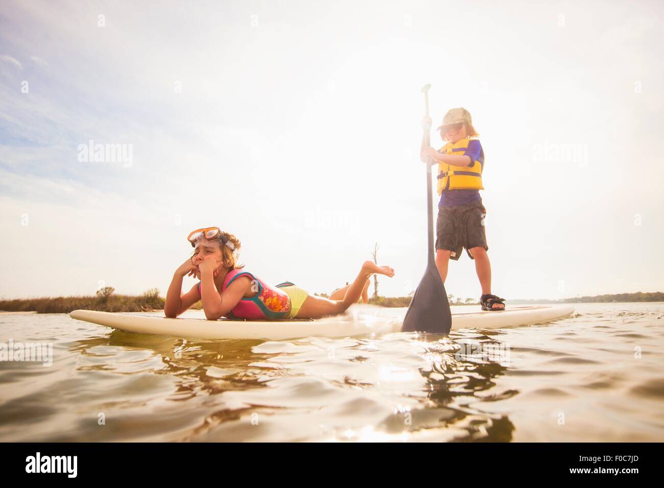 Boy standup paddleboarding with sister in the sound, Fort Walton, Florida, USA Stock Photo