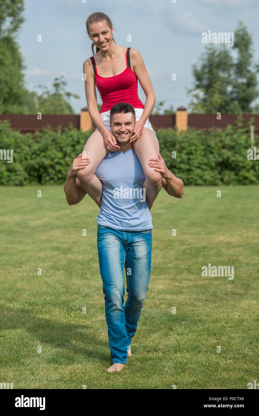 Full length portrait of happy young man carrying woman on shoulders in