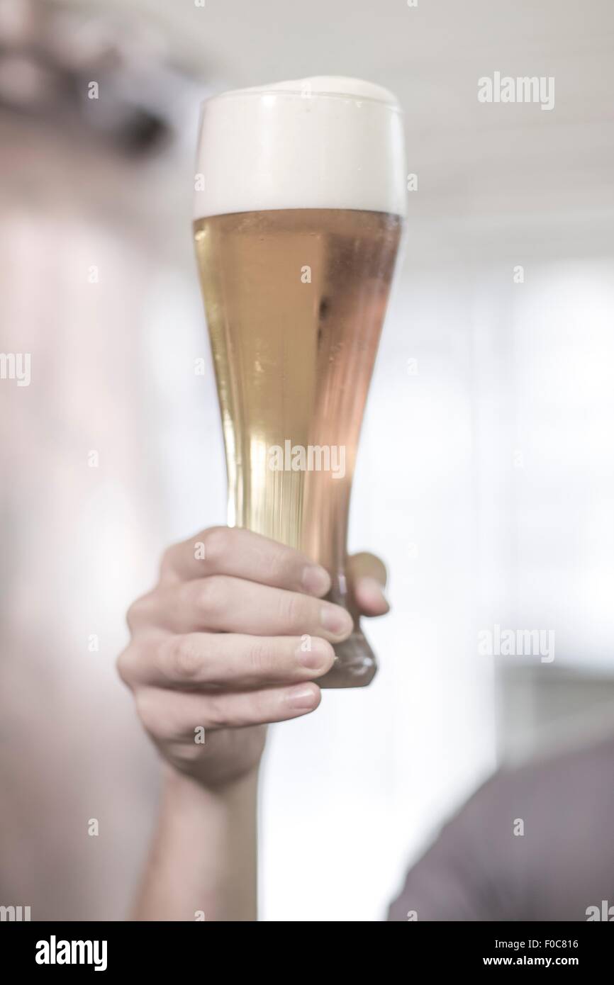 Brewer in brewery holding up a glass of beer Stock Photo